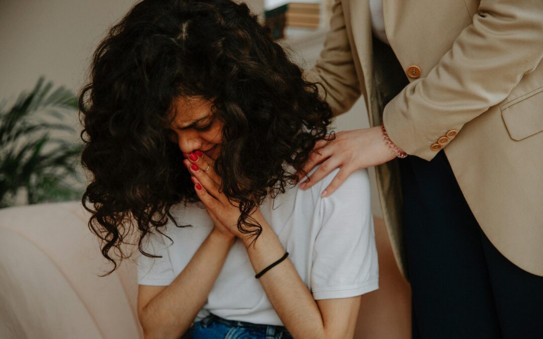 A young woman receiving comforting and emotional support during a therapy session.